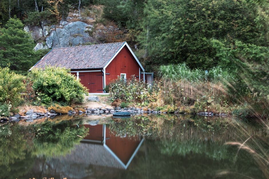 Maison rouge suédoise se reflétant dans un lac entouré de verdure