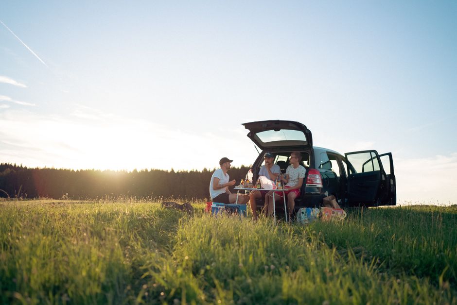 Pique-nique entre amis à côté d'une voiture à la campagne